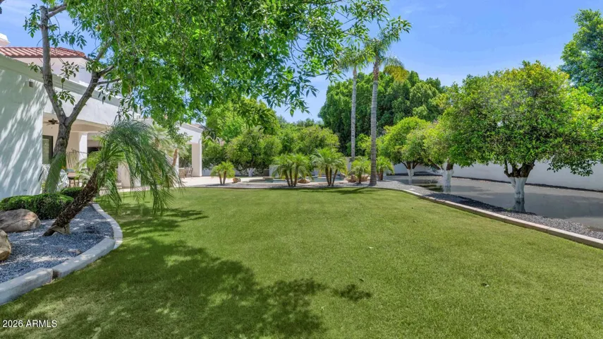 Irrigated Grounds and Mature Tree Perimeter
The full depth of the nearly-acre lot comes into view here, anchored by a mature tree perimeter that was carefully rehabilitated and restored as part of the home's comprehensive renovation. During the photo shoot, the flood irrigation began to fill along the tree line — a quiet reminder that this land is alive, tended, and thriving. At approximately $170 per year, the irrigation system delivers a lushness that simply cannot be replicated on a standard city lot.