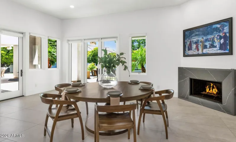 Generous proportions and an abundance of natural light define this family room, where the boundaries between inside and outside begin to dissolve. The covered patios accessible from the dining and fireplace areas create a natural indoor-outdoor rhythm that is quintessentially Arizona at its finest.