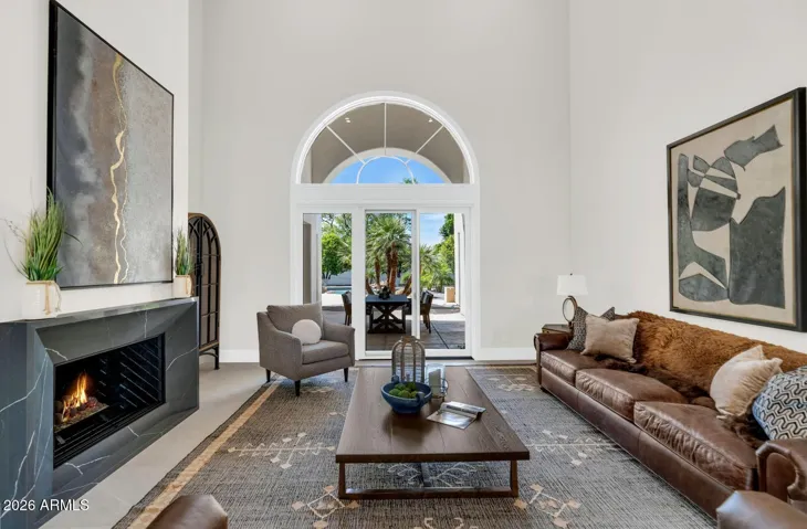 Sunlight moves through this room throughout the day, catching the warmth of the neutral palette and the clean lines of the contemporary fireplace. The soaring ceilings lend an openness that feels expansive without sacrificing intimacy — the kind of room that accommodates a quiet morning just as naturally as a room full of guests.