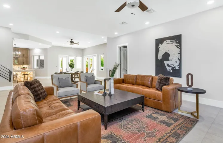 The family room anchors the great room with a warmth that is immediate and effortless. Rich cognac leather sofas, layered rugs, and an easy flow to both the kitchen and dining areas make this the space where everyone naturally gravitates — morning coffee, game nights, and everything in between.