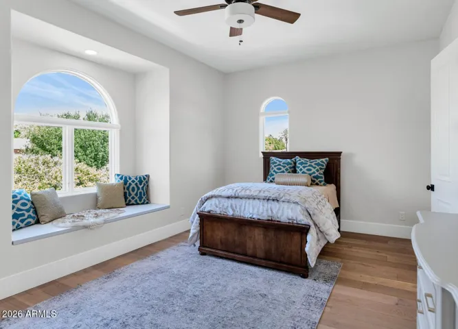This Jack & Jill Bedroom has an oversized arched window anchors this second-floor bedroom, framing a view of the grounds while flooding the space with warm natural light. Beneath the window, a generous built-in window seat with hidden storage adds a layer of charm and practicality that buyers rarely find in a home at any price point.