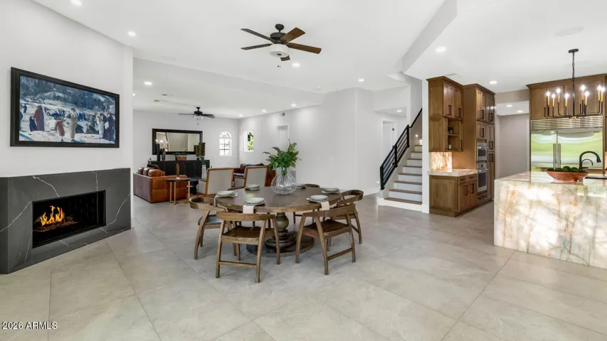 The family room portion of the great room is anchored by a fireplace and framed by windows that bring the outdoors in. Two walls of the great room open directly to covered patios, allowing the living space to expand effortlessly into the Arizona evening — a detail that transforms everyday living into something exceptional.