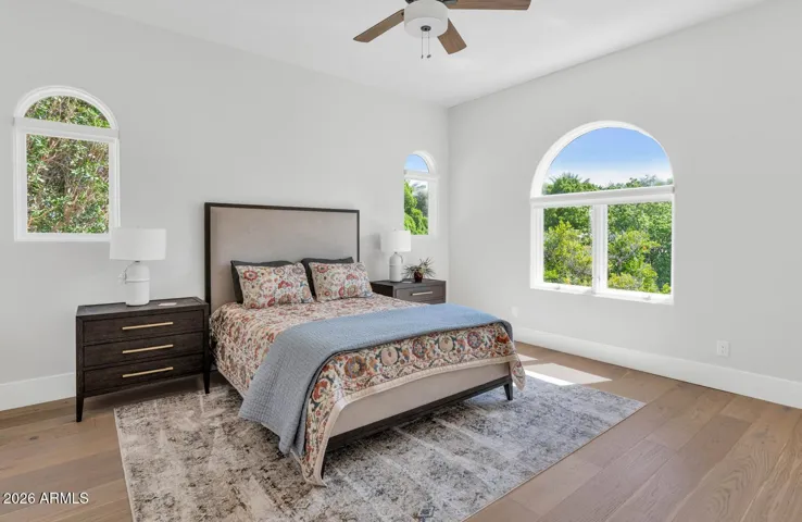 A generous second-floor bedroom with warm hardwood flooring, an arched window framing a garden view, and access to the dedicated hall bathroom. Comfortable, well-finished, and ready to welcome family or guests without a single compromise.