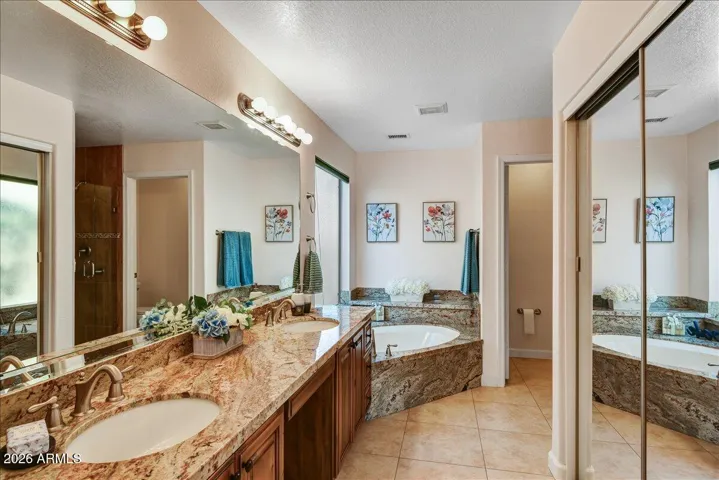 The primary ensuite is designed for relaxation with a dual-sink vanity, a separate soaking tub, and a walk-in shower. Granite counters, custom cabinetry and tile shower.