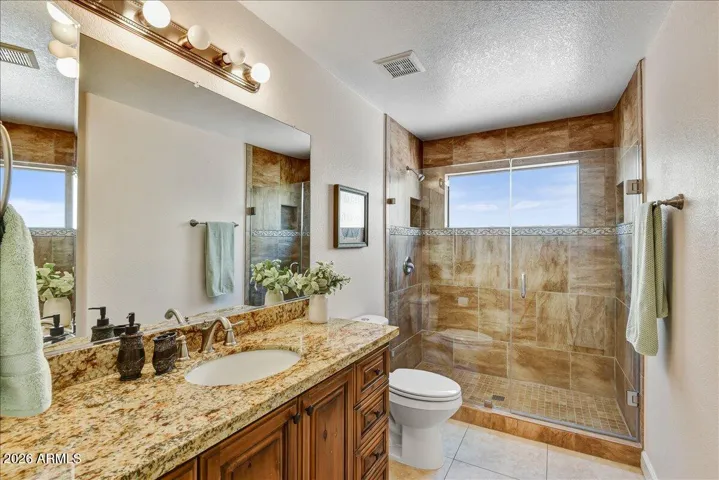 The guest bathroom is conveniently located off of the secondary primary and has been tastefully updated with granite counters, custom cabinets and tile shower