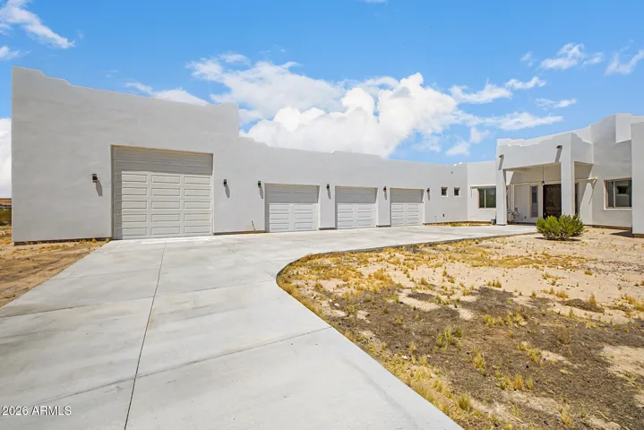 Bold contemporary desert estate set on expansive acreage with a striking circular drive, 6-car garage capacity including a drive-through bay, and breathtaking mountain views in every direction