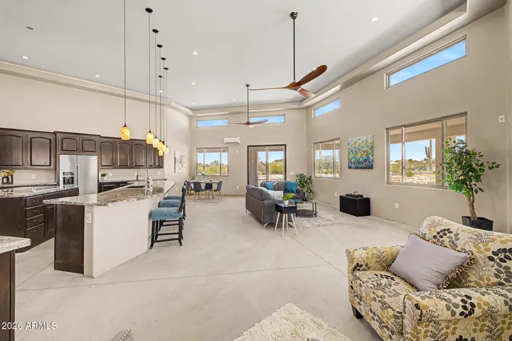 Soaring ceilings rise dramatically throughout the home, featuring a stunning coffered tray design in the great room that adds architectural depth, while clerestory windows positioned high on the walls flood the space with natural light and frame the endless desert sky above.
