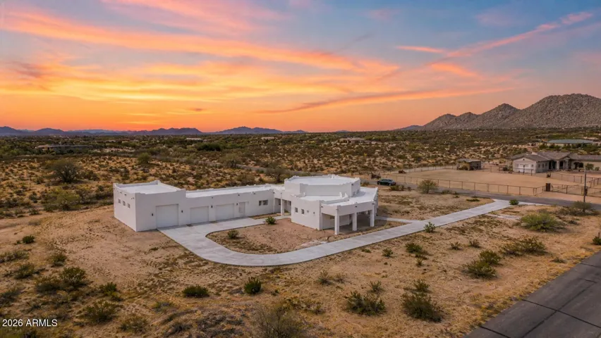 Bold contemporary desert estate set on expansive acreage with a striking circular drive, 6-car garage capacity including a drive-through bay, and breathtaking mountain views in every direction