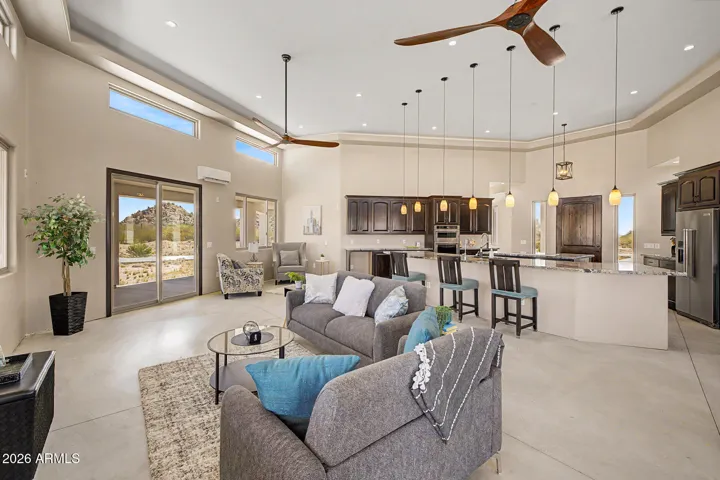 Soaring ceilings rise dramatically throughout the home, featuring a stunning coffered tray design in the great room that adds architectural depth, while clerestory windows positioned high on the walls flood the space with natural light and frame the endless desert sky above.