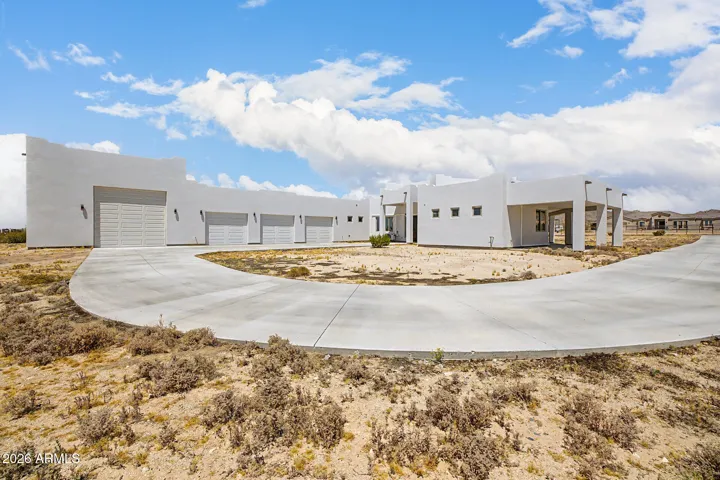 Bold contemporary desert estate set on expansive acreage with a striking circular drive, 6-car garage capacity including a drive-through bay, and breathtaking mountain views in every direction
