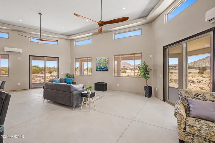 Soaring ceilings rise dramatically throughout the home, featuring a stunning coffered tray design in the great room that adds architectural depth, while clerestory windows positioned high on the walls flood the space with natural light and frame the endless desert sky above.