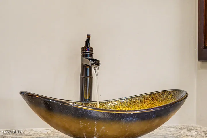 The primary bath stuns with dual artisan vessel sinks on a granite vanity.