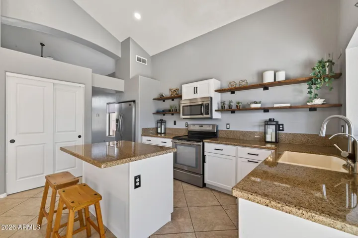 Sleek white cabinetry, granite countertops, and stainless-steel appliances offer style and functionality.