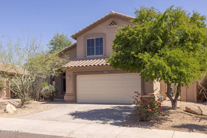 The front yard of this home features xeriscape landscaping and mature trees.
