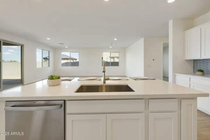 GOURMET KITCHEN WITH PAINTED CABINETS, QUARTZ COUNTERS, DESIGNER BACKSPLASH, GAS COOKTOP, BUILT-IN OVENS AND DESIGNER HOOD.