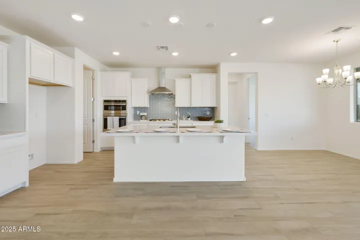 GOURMET KITCHEN WITH PAINTED CABINETS, QUARTZ COUNTERS, DESIGNER BACKSPLASH, GAS COOKTOP, BUILT-IN OVENS AND DESIGNER HOOD.