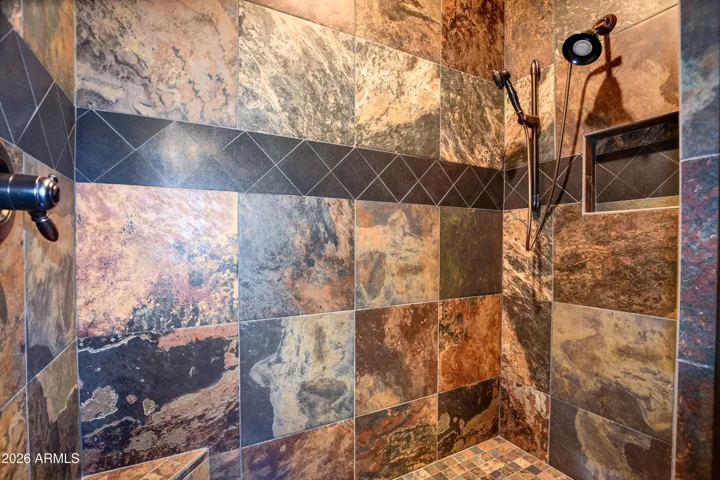Large walk in shower with Natural Stone slate shower floor to ceiling with black diamond accents, corner shower stool