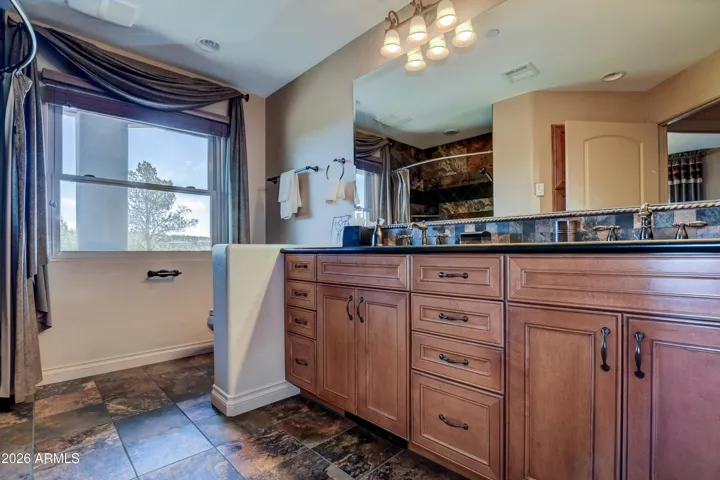 Features tub and shower combination, natural stone slate tile floors, double vanity sinks, slate countertops and beveled expansive mirror