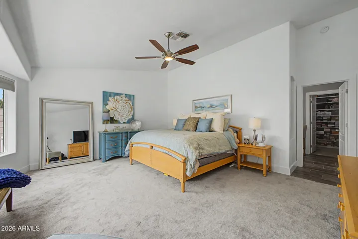 Generous primary bedroom with soaring ceilings, a ceiling fan for added comfort, and ample space for both furnishings and a sitting area.