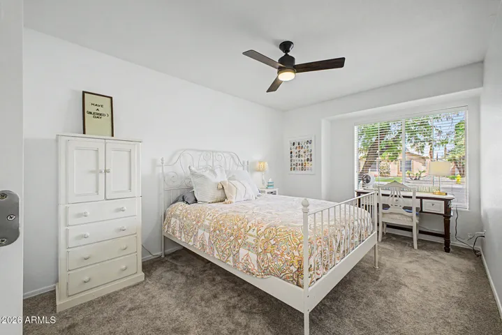 Bright secondary bedroom with newer carpet, ceiling fan, and charming window alcove.