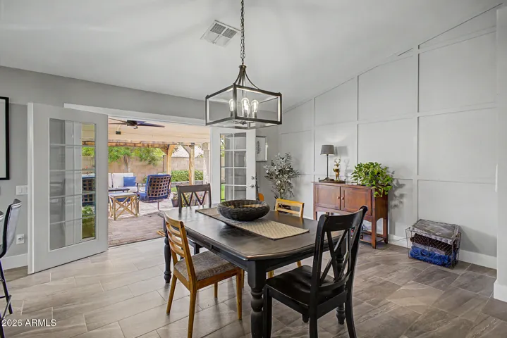 Dining area with wall with custom accent wall, double french doors open to rear covered patio