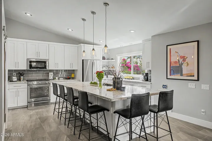 Bright, open remodeled kitchen in 2019 with oversized island, pendant lighting, and seating for six.