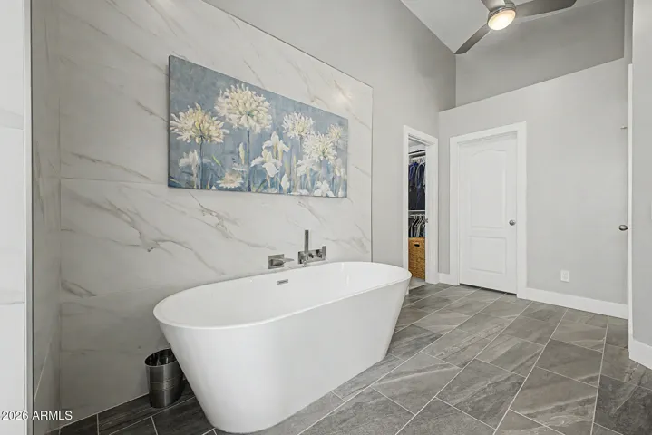 Calming soaking tub area with modern finishes and access to walk-in closet.