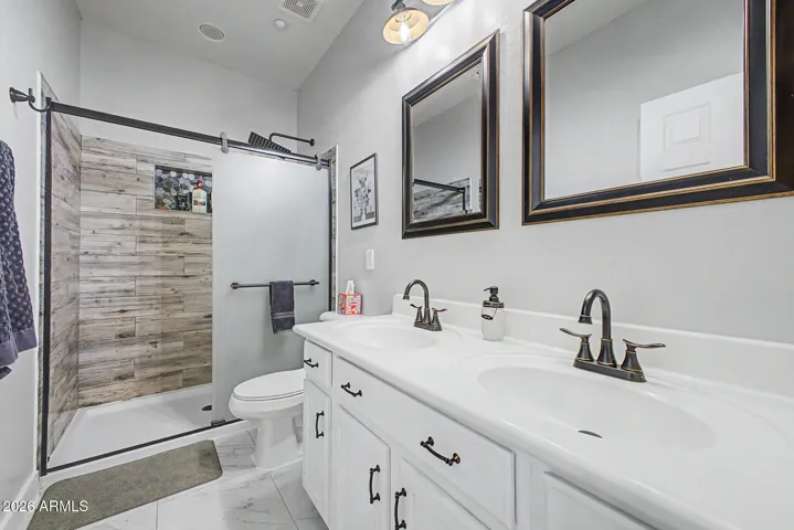Secondary bathroom upstairs is updated with dual sinks and a clean aesthetic.