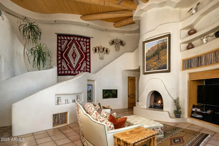 Vibrant textures and architectural charm define this inviting family room. Featuring a custom fireplace, natural wood ceiling, and artful décor niches, this area offers a cozy gathering space in this hilltop estate.