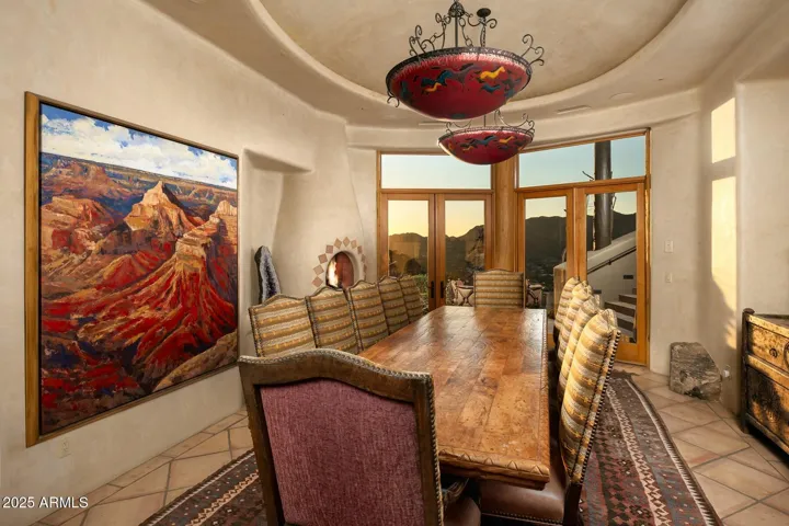 This elegant dining room features access to a private patio, offering seamless indoor-outdoor living. Dramatic lighting, curved architecture, and expansive mountain views create a refined yet relaxed entertaining space