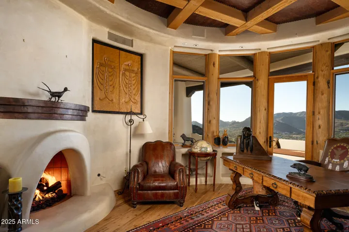 This custom office features a corner fireplace, handcrafted woodwork, and wraparound windows framing desert and city lights. Ideal for quiet focus or inspired creativity within this luxury Paradise Valley retreat.