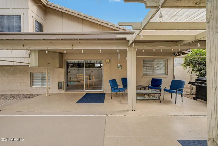 Back patio with covered seating area and view of the home’s rear elevation, offering functional and comfortable outdoor space.