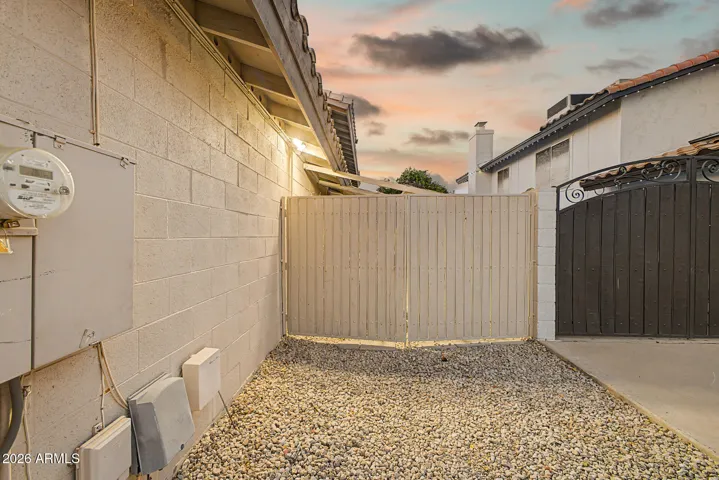 Side yard with RV gate access, low-maintenance gravel landscaping, and functional space for storage or additional parking.