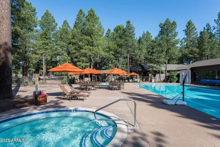 Resort-inspired community pool and spa area featuring lounge seating, shaded tables, and beautiful pine tree surroundings in Flagstaff.