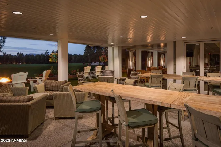 Inviting outdoor clubhouse patio with comfortable seating, fire features, and spacious dining areas overlooking lush community grounds in Flagstaff.