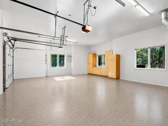 Expansive garage with custom storage cabinets, bright lighting, epoxy-coated floors, and exceptional space for hobbies and vehicle storage. Premium garage space featuring built-in cabinetry, epoxy flooring, overhead heater, and room for golf carts or additional recreational vehicles.