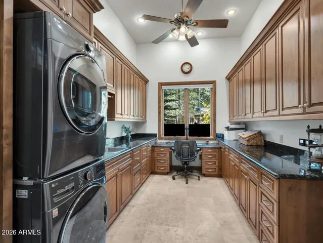 Large laundry and utility room featuring abundant cabinetry, granite counters, workspace area, and extensive storage for organization and convenience.