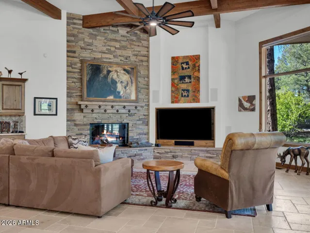 Warm and inviting gathering room featuring a dramatic floor-to-ceiling stone fireplace, expansive windows, and custom finishes that create the perfect mountain retreat atmosphere.