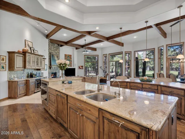 Bright gourmet kitchen with expansive windows, double islands, custom cabinetry, and beautiful views of the surrounding pine forest and Meadow Golf Course.