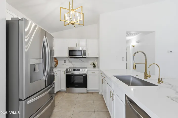 Deep single sink, gold faucets, hardware and lighting.