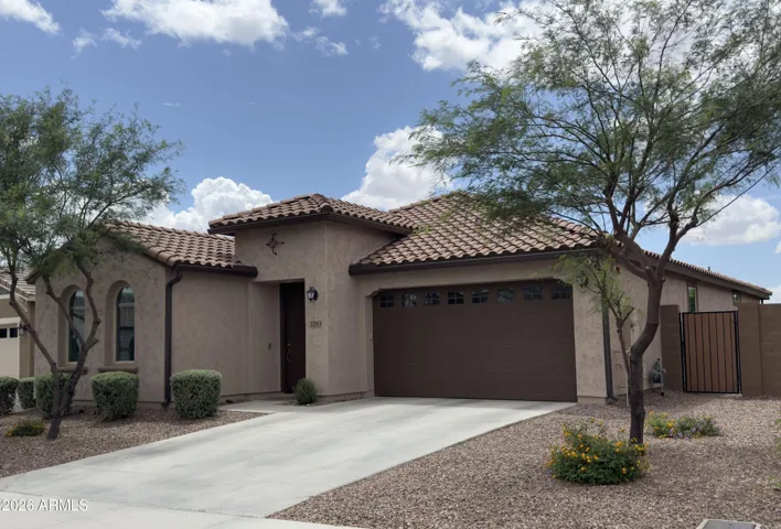 Inviting front exterior of this Peoria home featuring desert landscaping, mature trees, and a 2-car garage with extended driveway. Clean curb appeal and low-maintenance design enhance energy efficiency and everyday convenience.