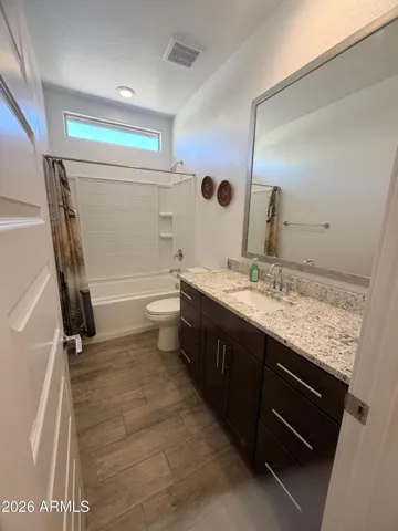 Bright full bathroom featuring granite vanity, large mirror, and upgraded lighting. Functional layout with clean finishes adds value and convenience.