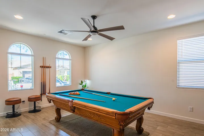 Versatile game room with natural light, ceiling fan, and durable flooring. Ideal as a media room, home office, or recreation space in this open-concept Peoria property.