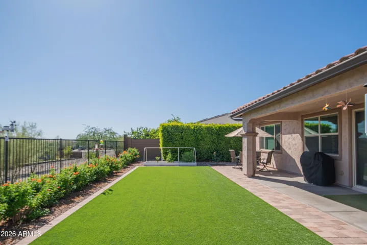 Beautiful backyard with artificial turf, paver accents, and privacy landscaping. Energy-efficient outdoor space perfect for relaxing or hosting.