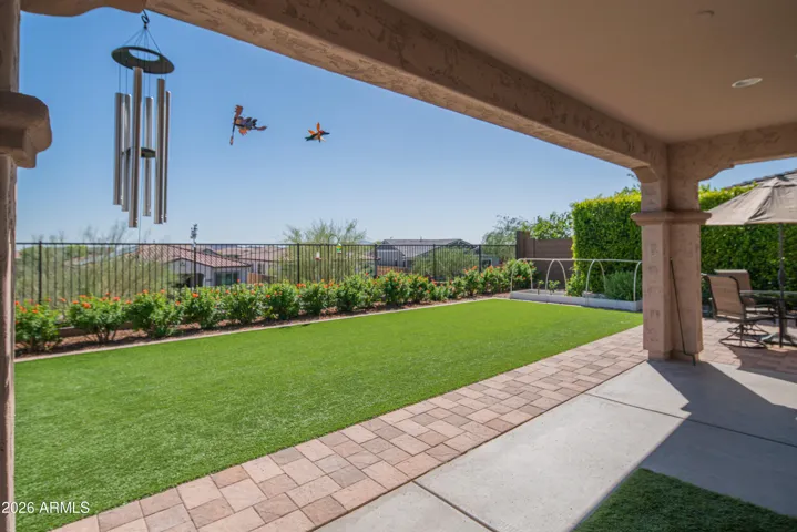 Private backyard retreat with covered patio, artificial turf, and paver walkway. Enjoy mountain views and low-maintenance landscaping, perfect for outdoor entertaining in this Peoria home.