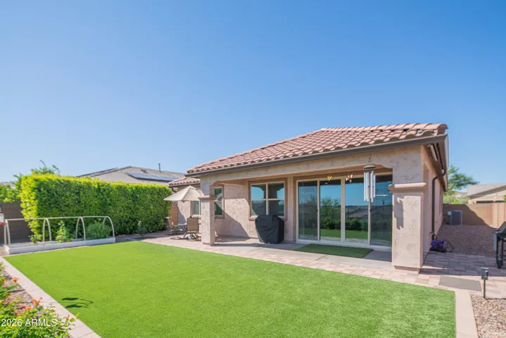 Expansive backyard with covered patio, artificial turf, and low-maintenance landscaping. Designed for outdoor living and entertaining with seamless indoor-outdoor flow.