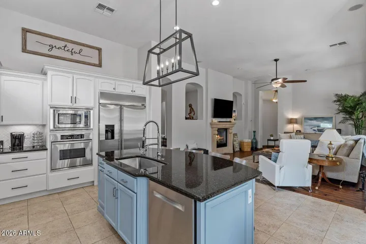 Beautiful lighting and stylish island with granite and oversized stainless sink and fixtures.