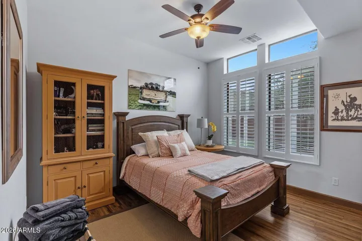 Beautiful Bedroom with wood tile flooring, shutters through out this home and fan.