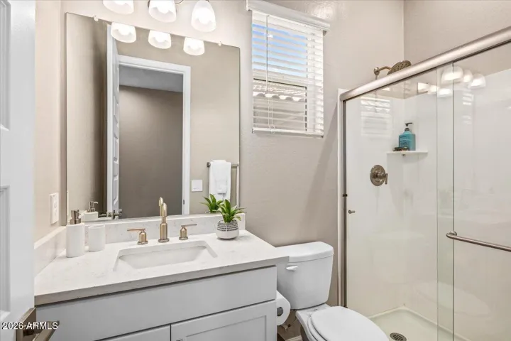 Vanity with quartz countertop. Walk-in shower.