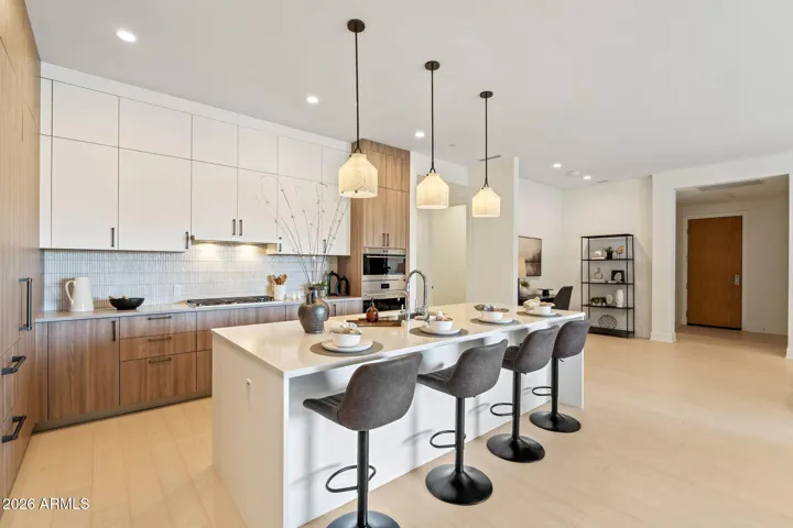 A striking oversized island with quartz counters anchors the space, offering seating and a natural gathering point for guests.